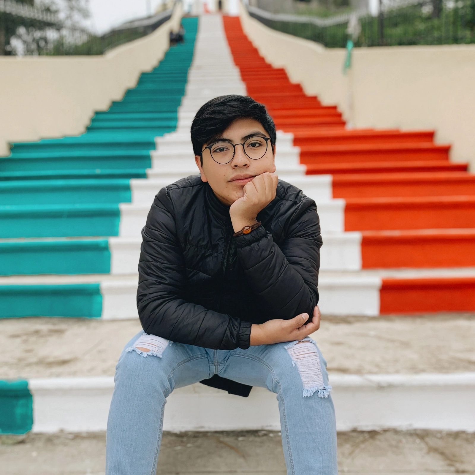 A young man sitting on a colorful staircase.