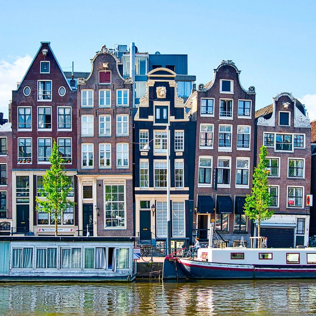 A canal with old warehouses and houseboats in Amsterdam.
