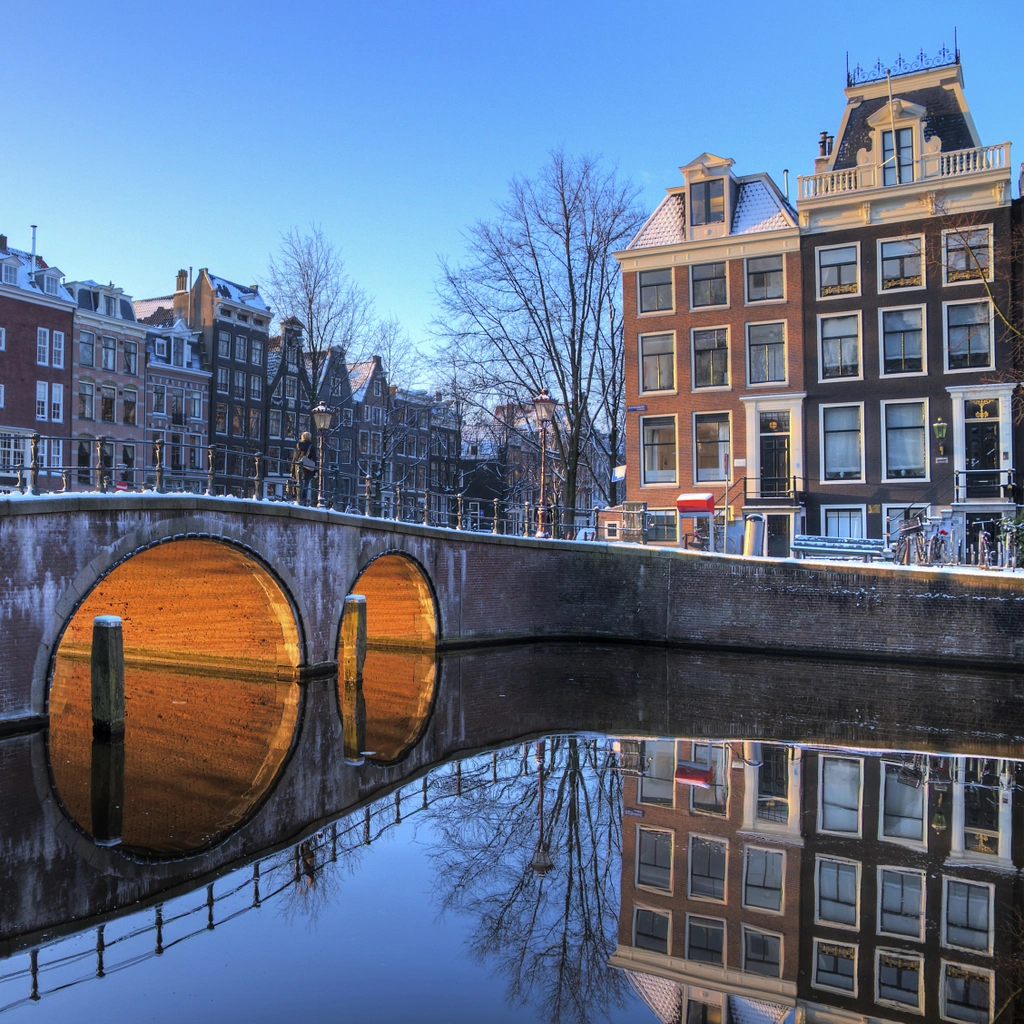 A winter view of a canal and warehouses in Amsterdam.